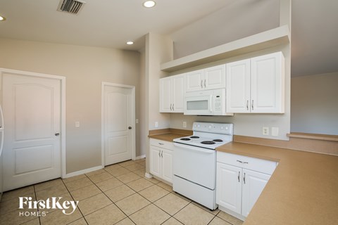 A kitchen with white appliances and cabinets is on the market.
