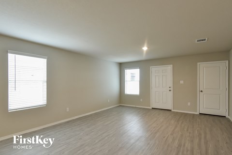 the spacious living room with wood flooring and a white door