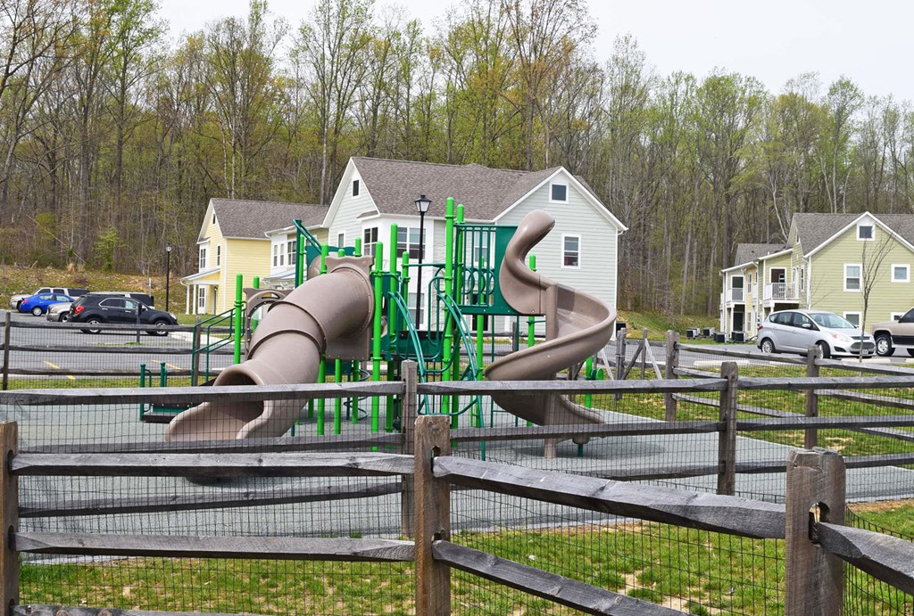 a playground with slides and houses in a parking lot