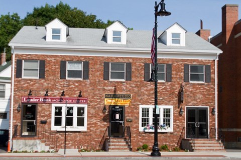 A brick building with a sign that says "Leader Bank Mortgage Center" on it.