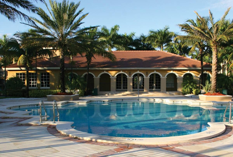 a swimming pool in front of a house with palm trees