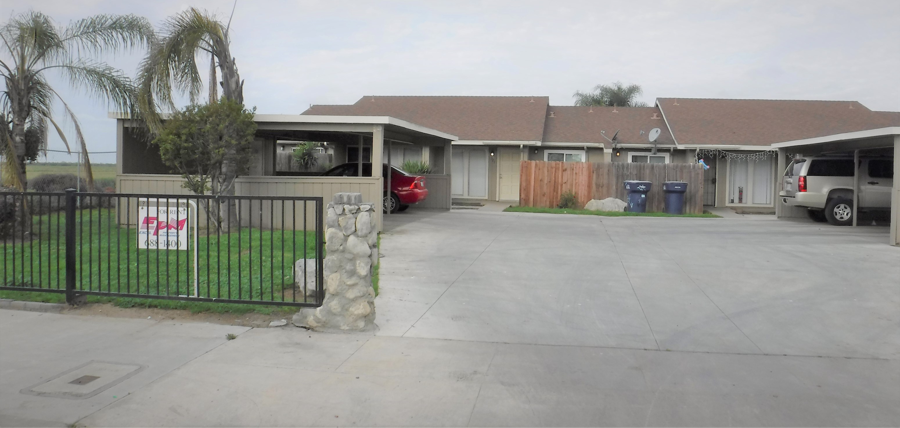 a house with a parking lot and a sign on the gate
