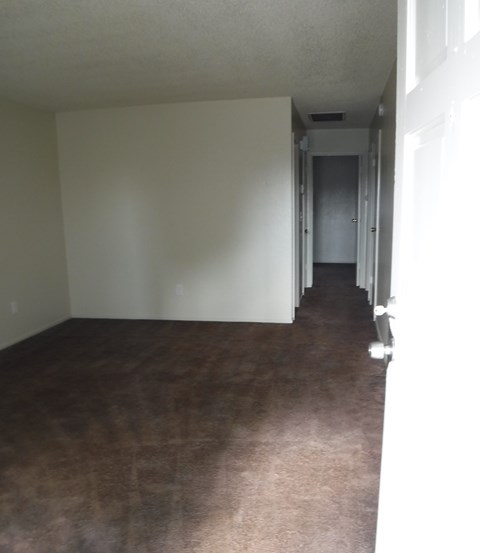 an empty living room with a wood floor and white walls
