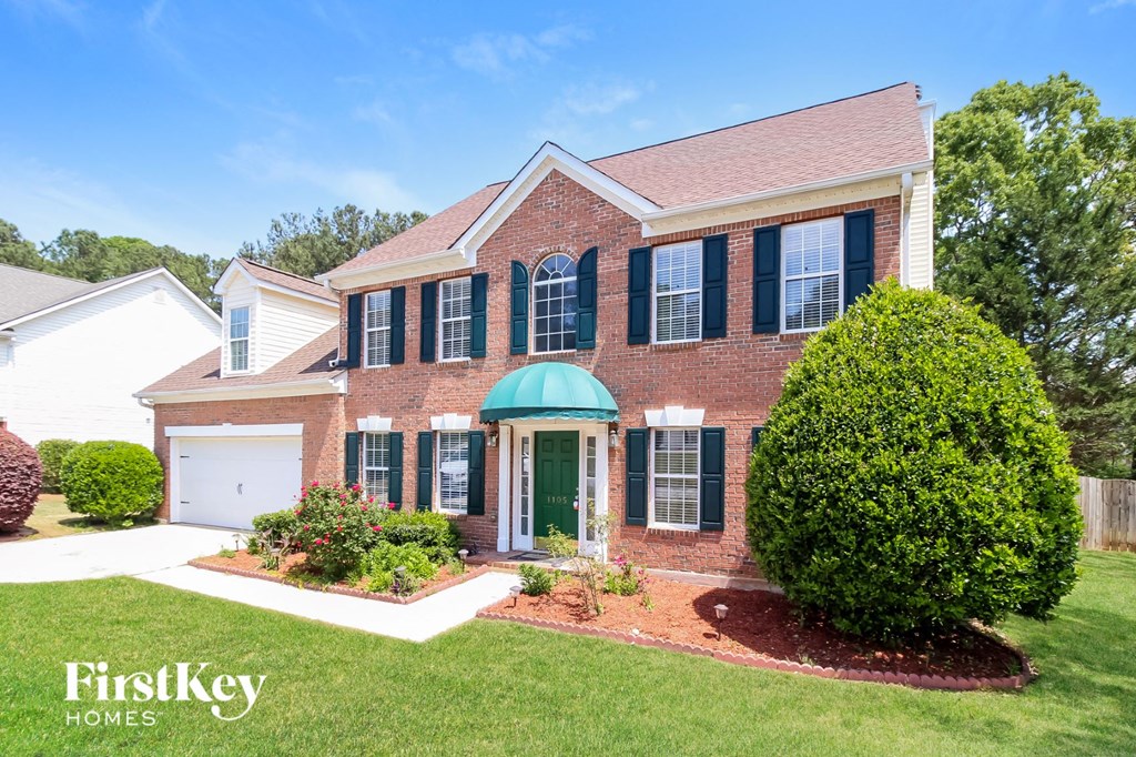 a brick house with black shutters and a green front door