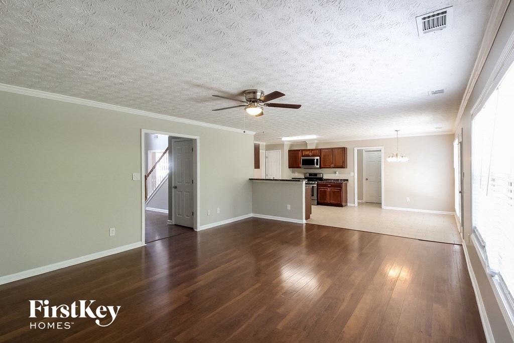 an empty living room and kitchen with wood floors and a ceiling fan