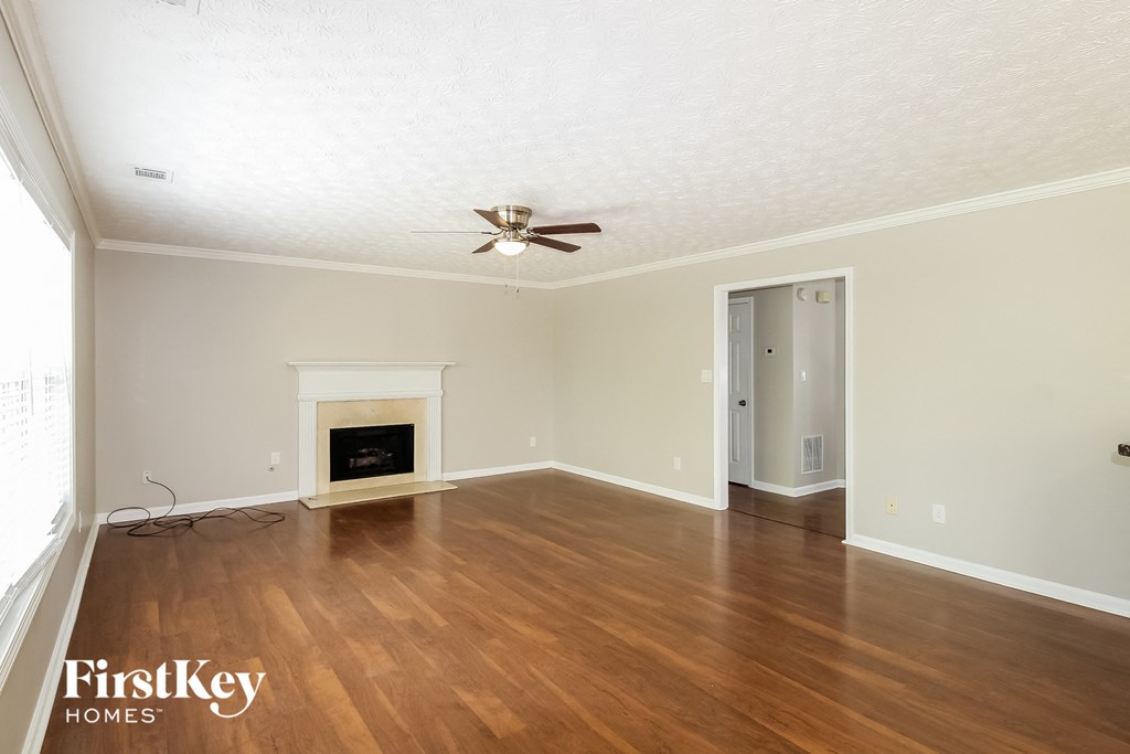a living room with a fireplace and wooden floors and a ceiling fan