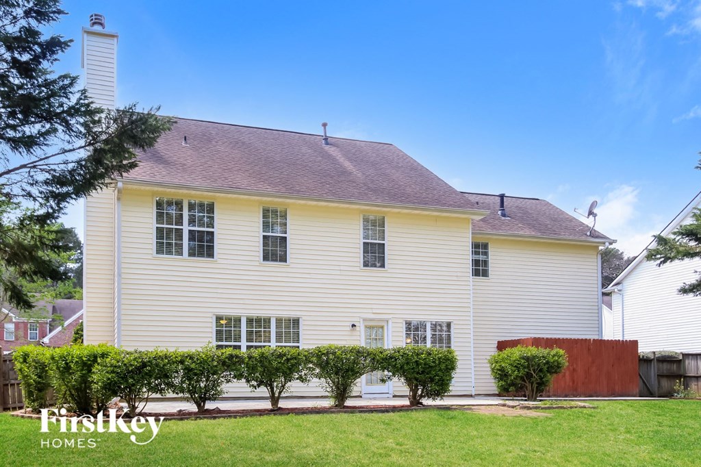 a large white house with a red fence and a green lawn