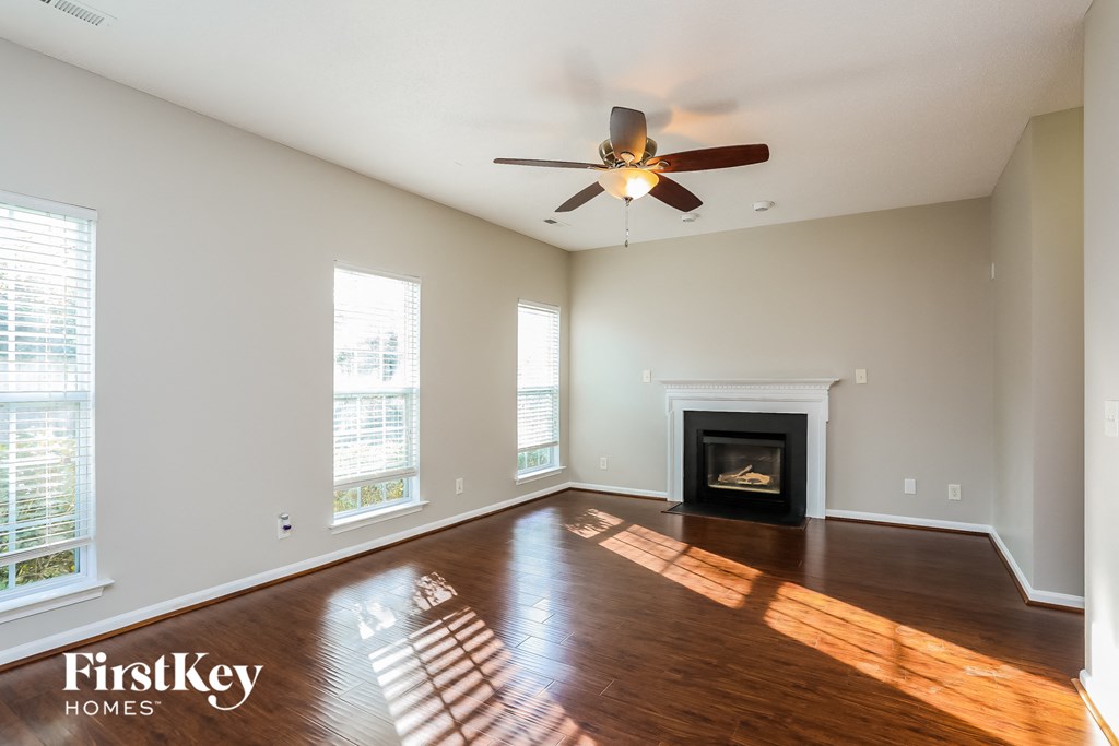 A spacious living room with a fireplace and a ceiling fan.