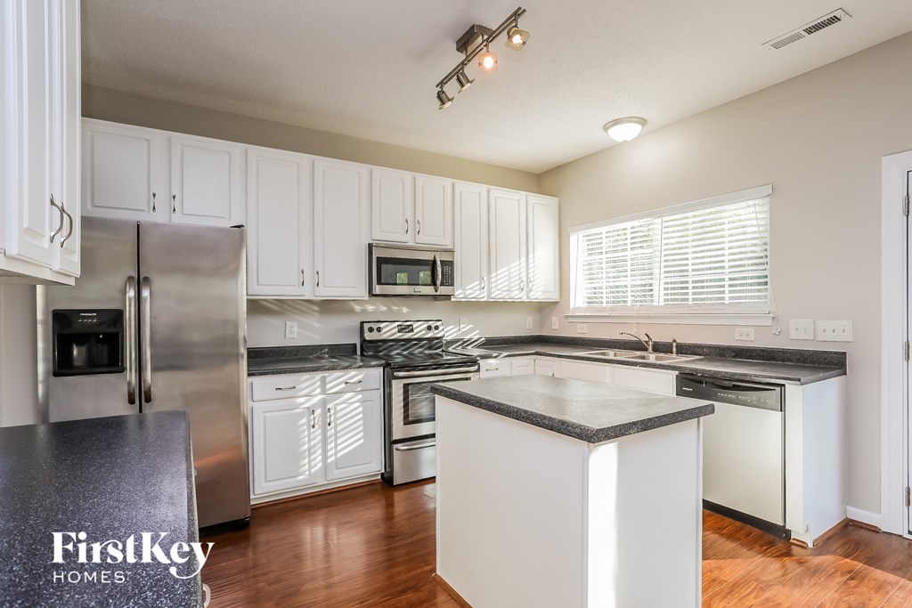A kitchen with white cabinets and a black countertop.