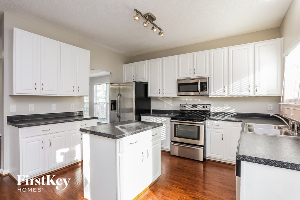 A kitchen with white cabinets and a black countertop.
