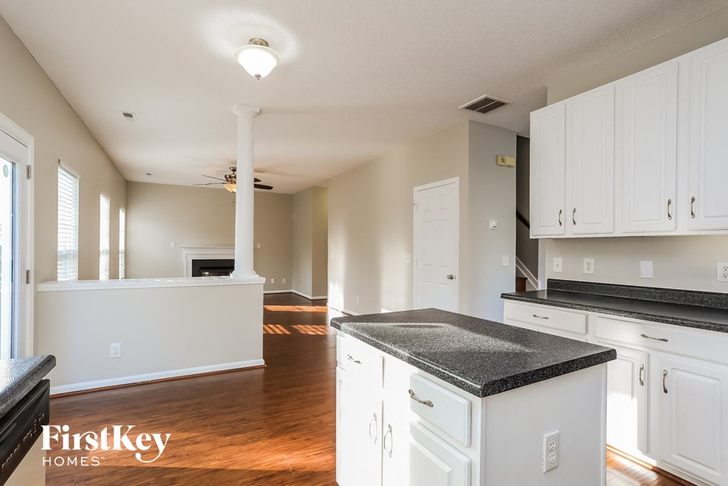 A kitchen with white cabinets and a black countertop.