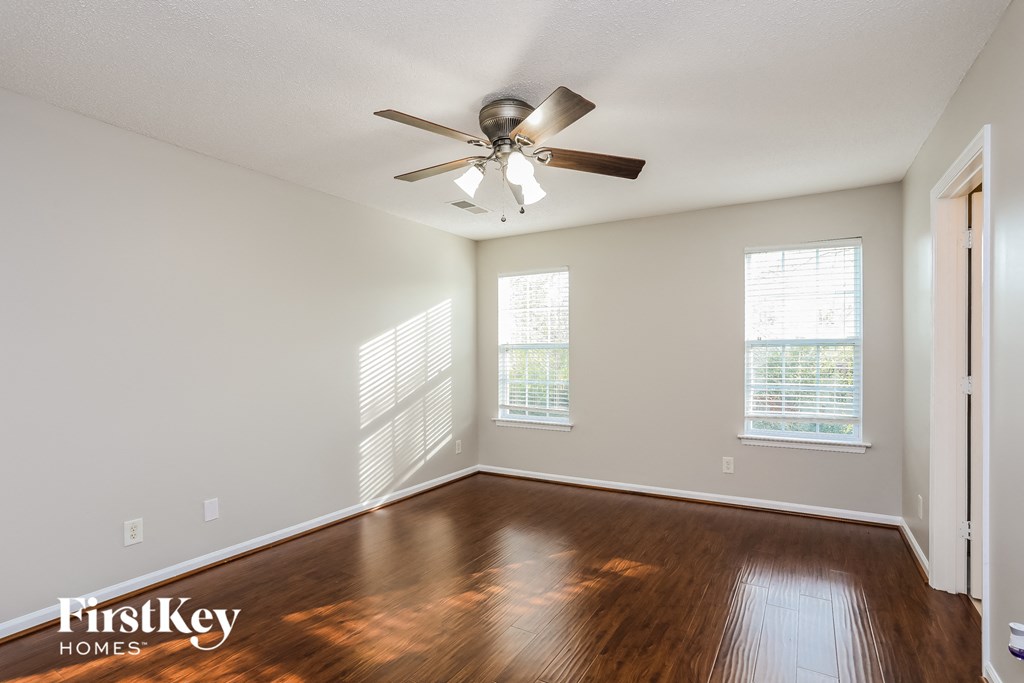 A room with a ceiling fan and wooden floors.
