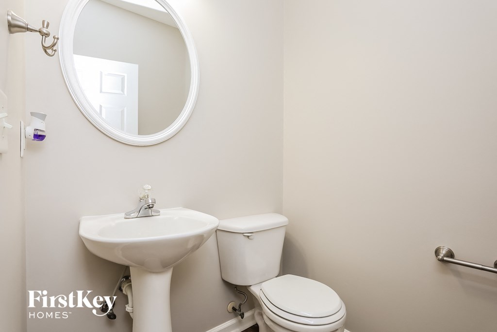 A white bathroom with a toilet, sink and mirror.