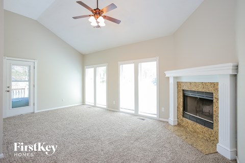 A spacious living room with a fireplace and a ceiling fan.