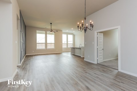 an empty living room and dining room with a chandelier