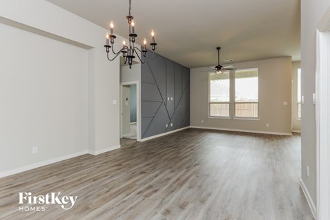 the living room and dining room of an empty house with a chandelier