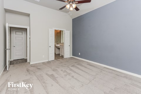 an empty living room with a ceiling fan and a door to a bathroom