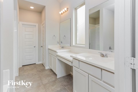 a white bathroom with two sinks and two mirrors