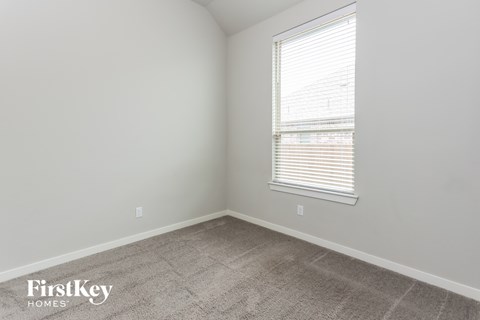 a bedroom with a window and a carpeted floor