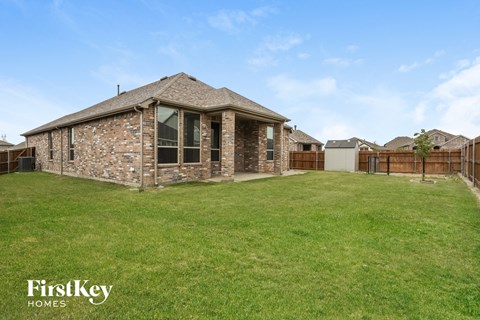 a backyard with a brick house and a wooden fence