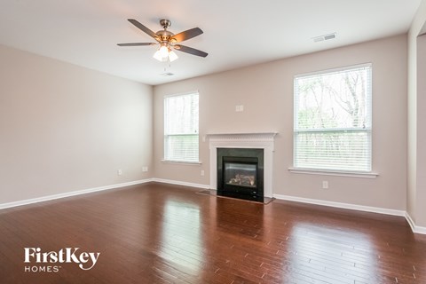 a empty living room with a ceiling fan and a fireplace