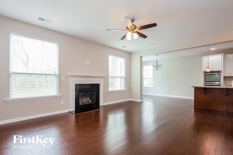 an empty living room with a fireplace and a ceiling fan