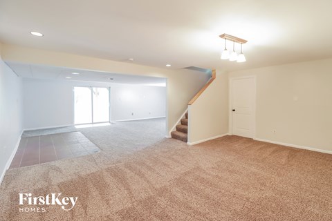 A spacious room with a staircase and a window.