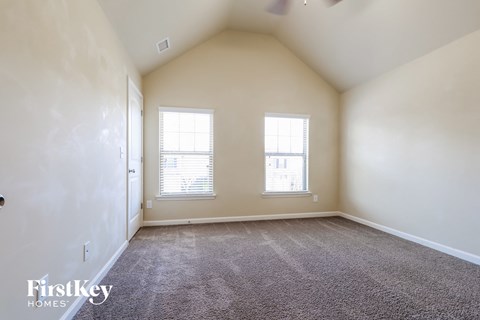 a spacious living room with two windows and carpeting