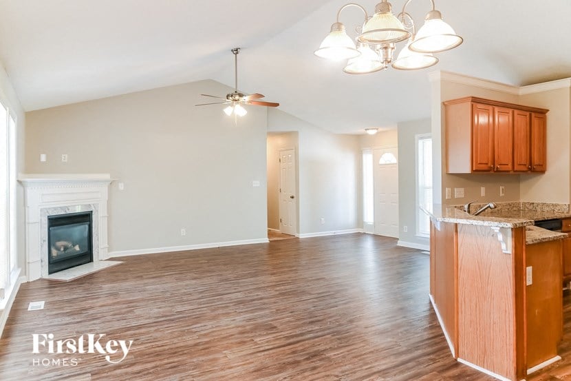 an empty living room with a fireplace and a kitchen
