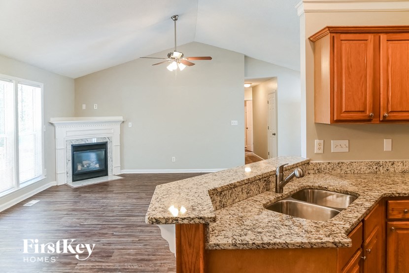 a kitchen with granite counter top and a living room with a fireplace