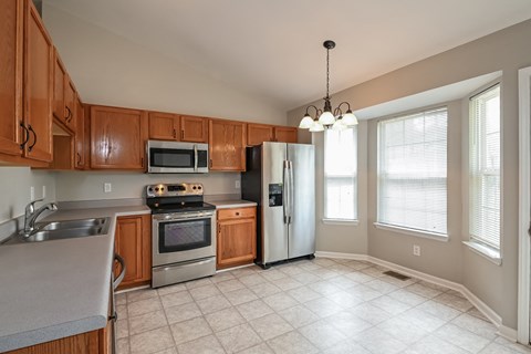 A kitchen with wooden cabinets and a stainless steel refrigerator.