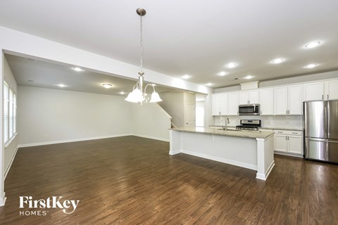 an open kitchen and living room with white cabinets and a kitchen island