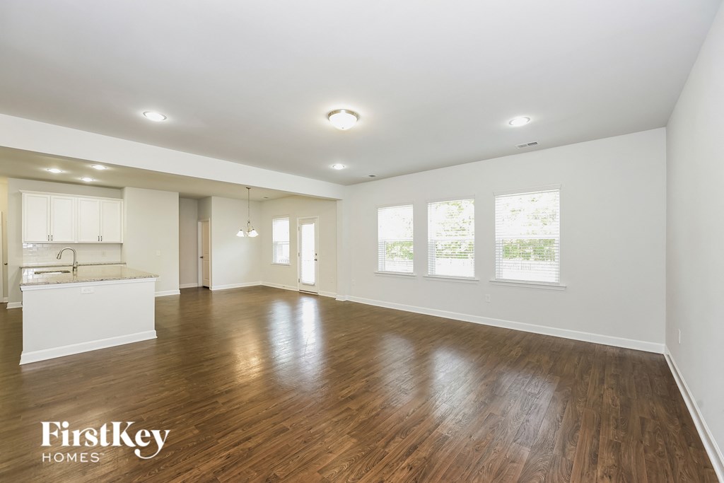 an empty living room and kitchen with wood floors and white walls