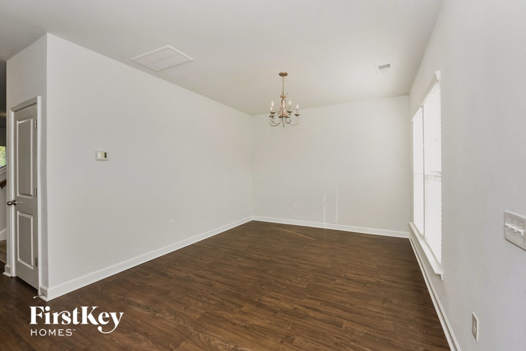 a living room with white walls and wood flooring and a chandelier