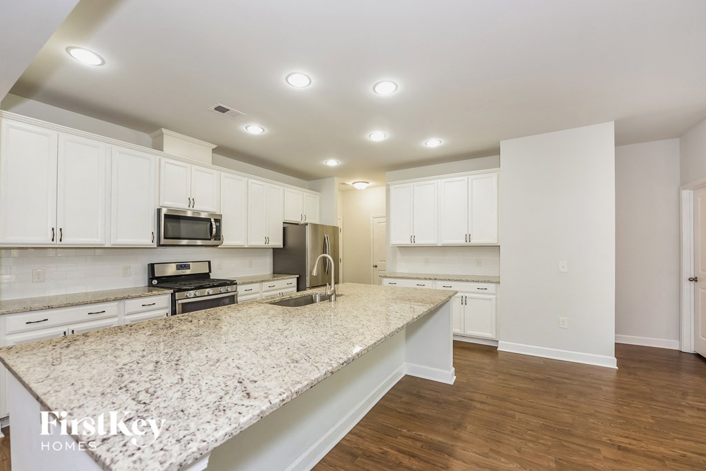 a kitchen with white cabinets and a marble counter top