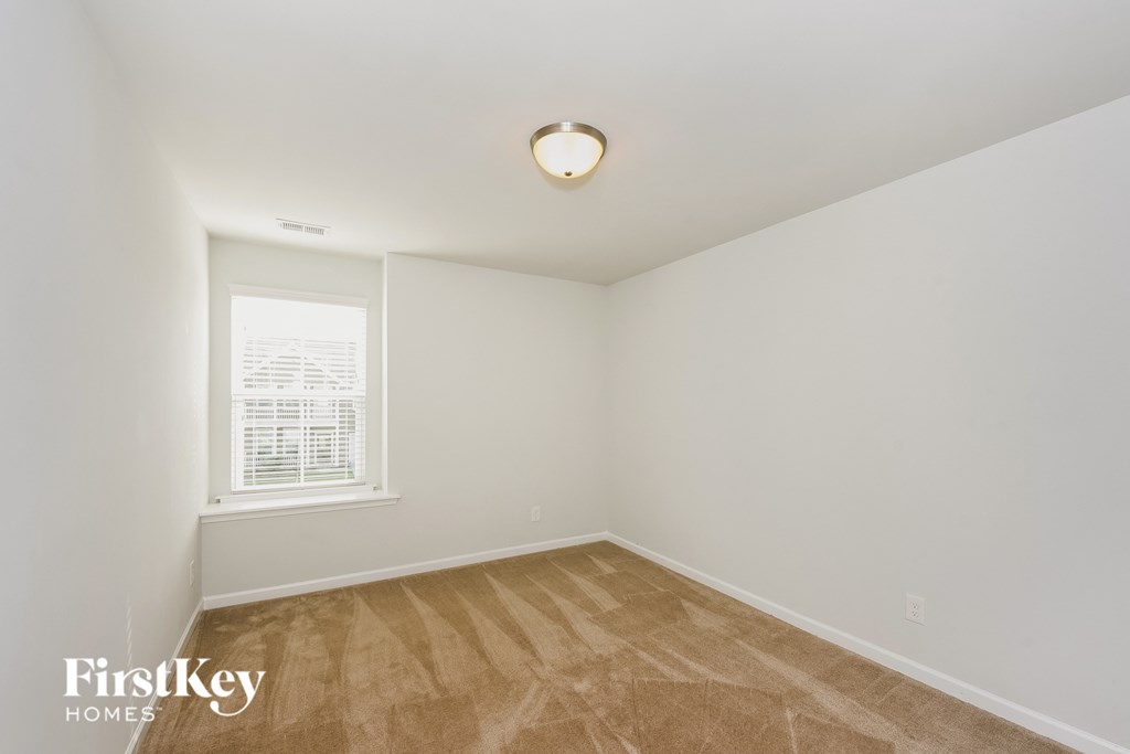 a bedroom with white walls and wood flooring and a window