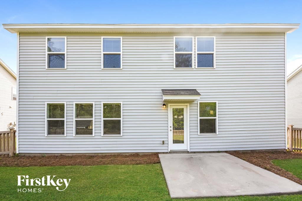 the front of a white house with a driveway and grass