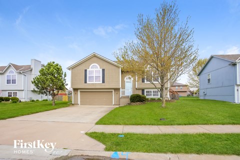 a beige house with a driveway and a lawn