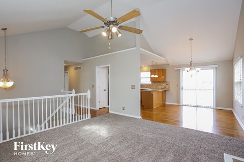 an empty living room with a ceiling fan and a kitchen