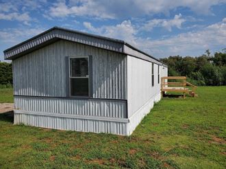 a small metal building in a field with a wooden deck