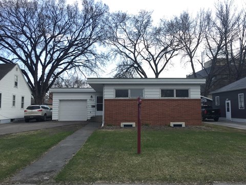the front of a house with a brick wall and a driveway