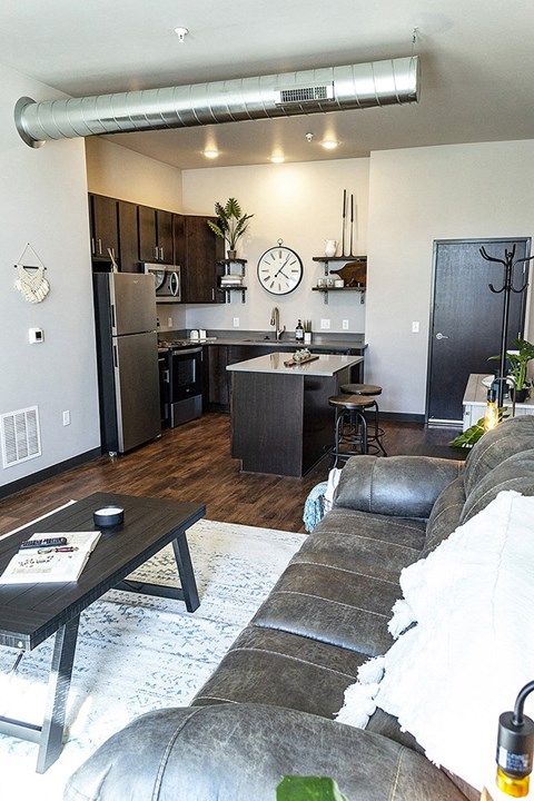 a living room and a kitchen with a clock on the wall