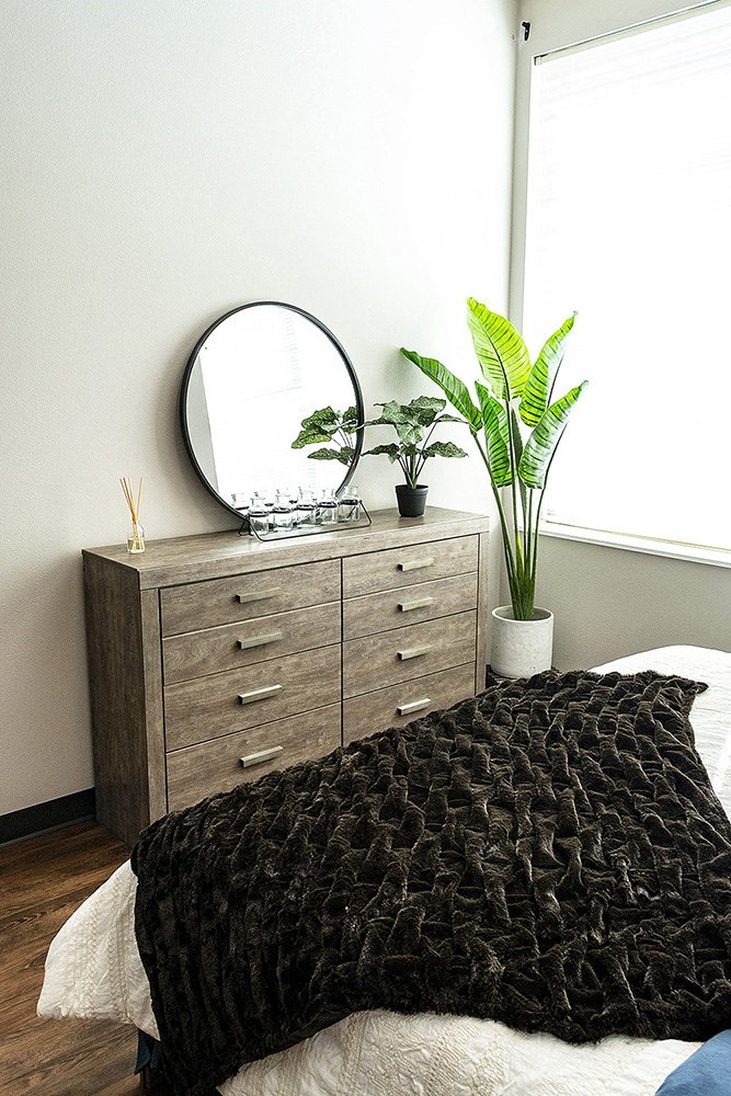 a bedroom with a bed and a mirror on a dresser