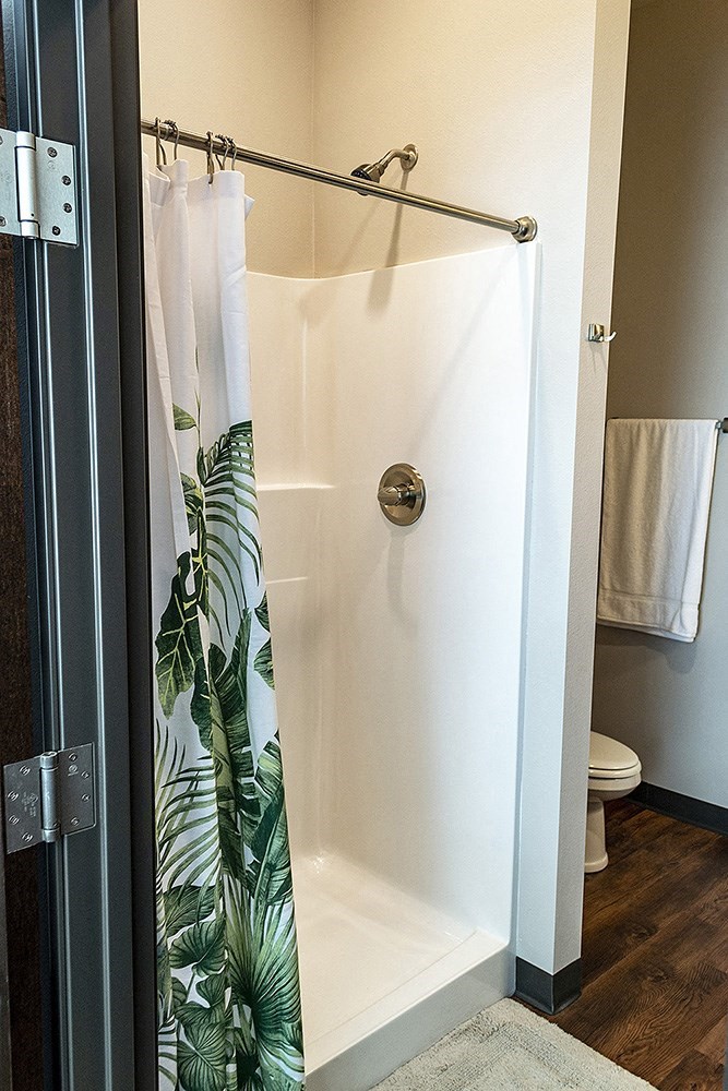a bathroom with a shower with a tropical shower curtain