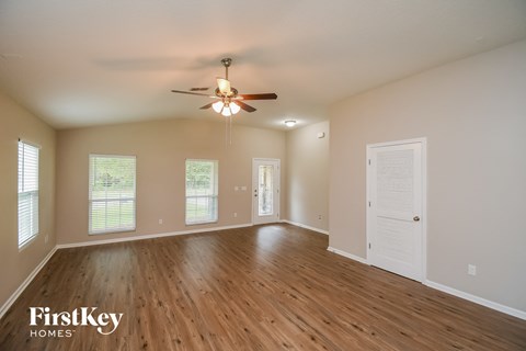 A spacious room with wooden floors and a ceiling fan.