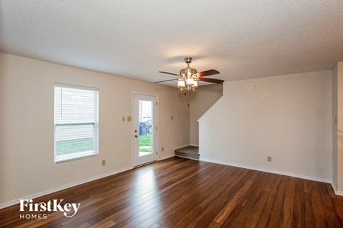 the living room and dining room with hardwood floors and a ceiling fan