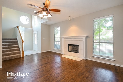 A spacious living room with a fireplace and a staircase.