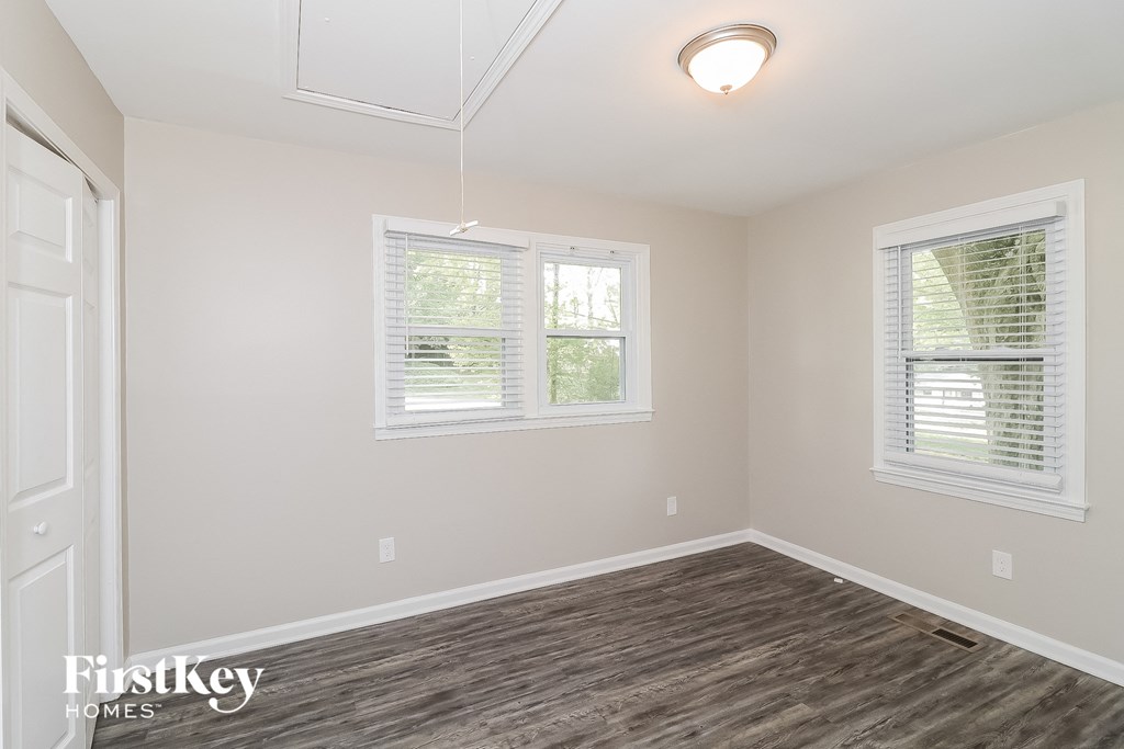 a bedroom with a hard wood floor and two windows