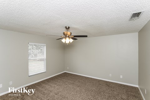 a bedroom with a ceiling fan and a carpet