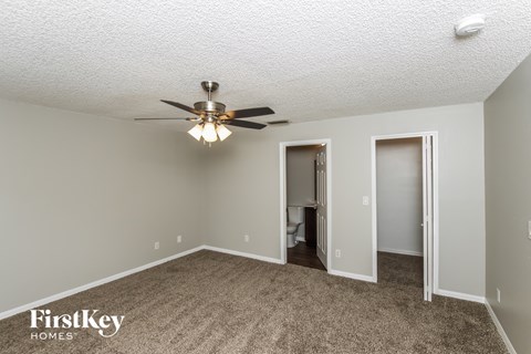 a living room with a ceiling fan and a door to a bathroom